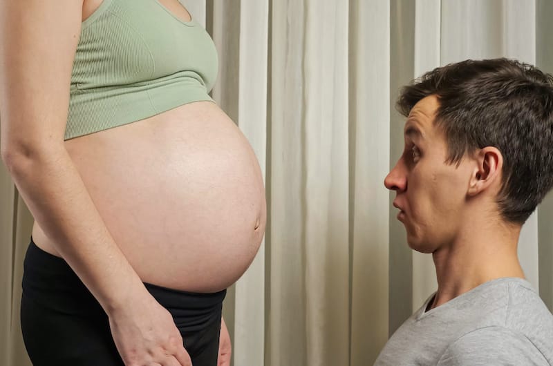 A husband is shocked as he stares at his pregnant wife's growing belly