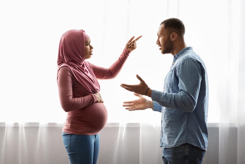 A pregnant couple are looking at each other and are in the middle of an arguement