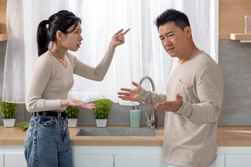 A married couple is having an argument in the kitchen about whether they should visit one of their parents or not