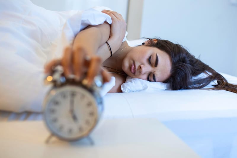 A young married woman is shown turning off her alarm clock and deciding to stay asleep longer