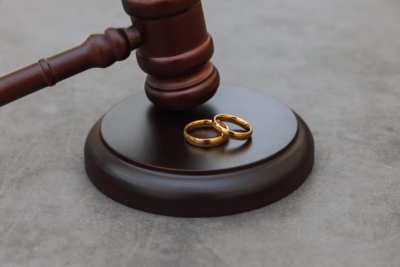 A gavel is shown next to 2 wedding rings, to represent the government being involved in a court marriage.