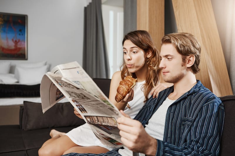 A young couple are sitting together in the morning reading the morning newspaper