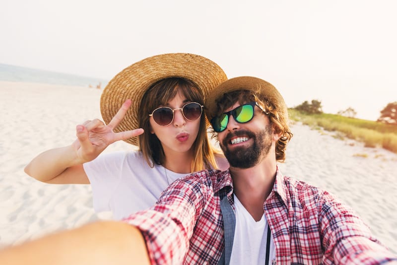 A young married couple is having fun and taking a selfie picture at the beach