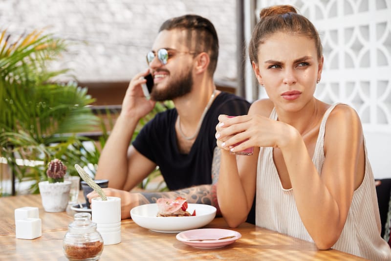 A wife is noticeably upset as her husband is on the phone and not giving her attention