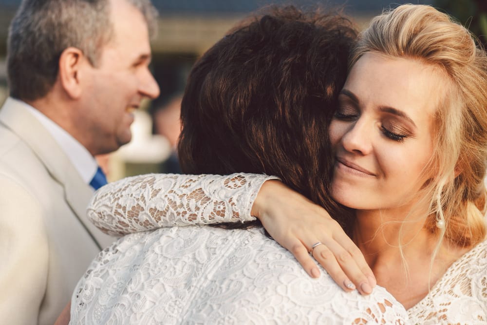 A young bride is hugging her mom after just getting married