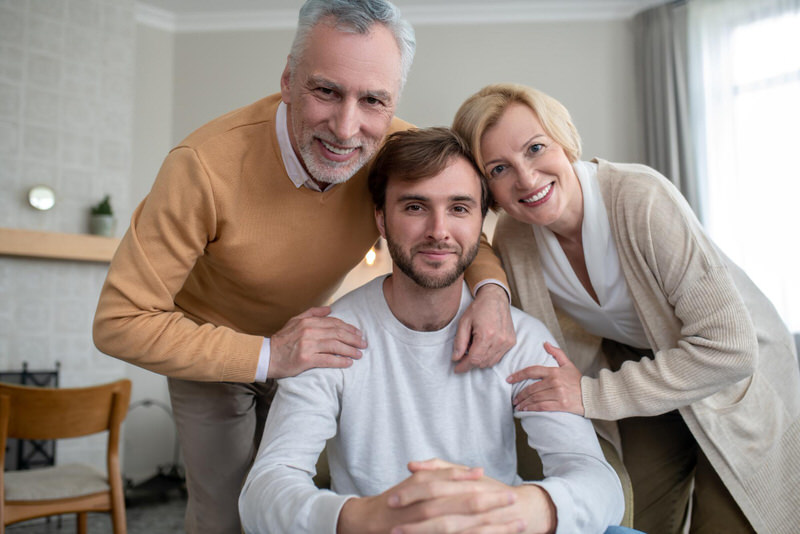 A young man is taking a picture with his  parents