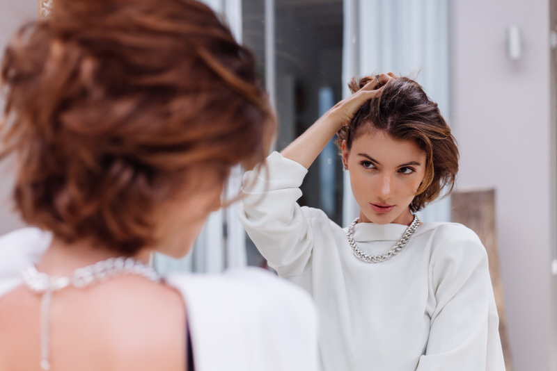 A young woman is obsessed with herself as she looks at herself in the mirror